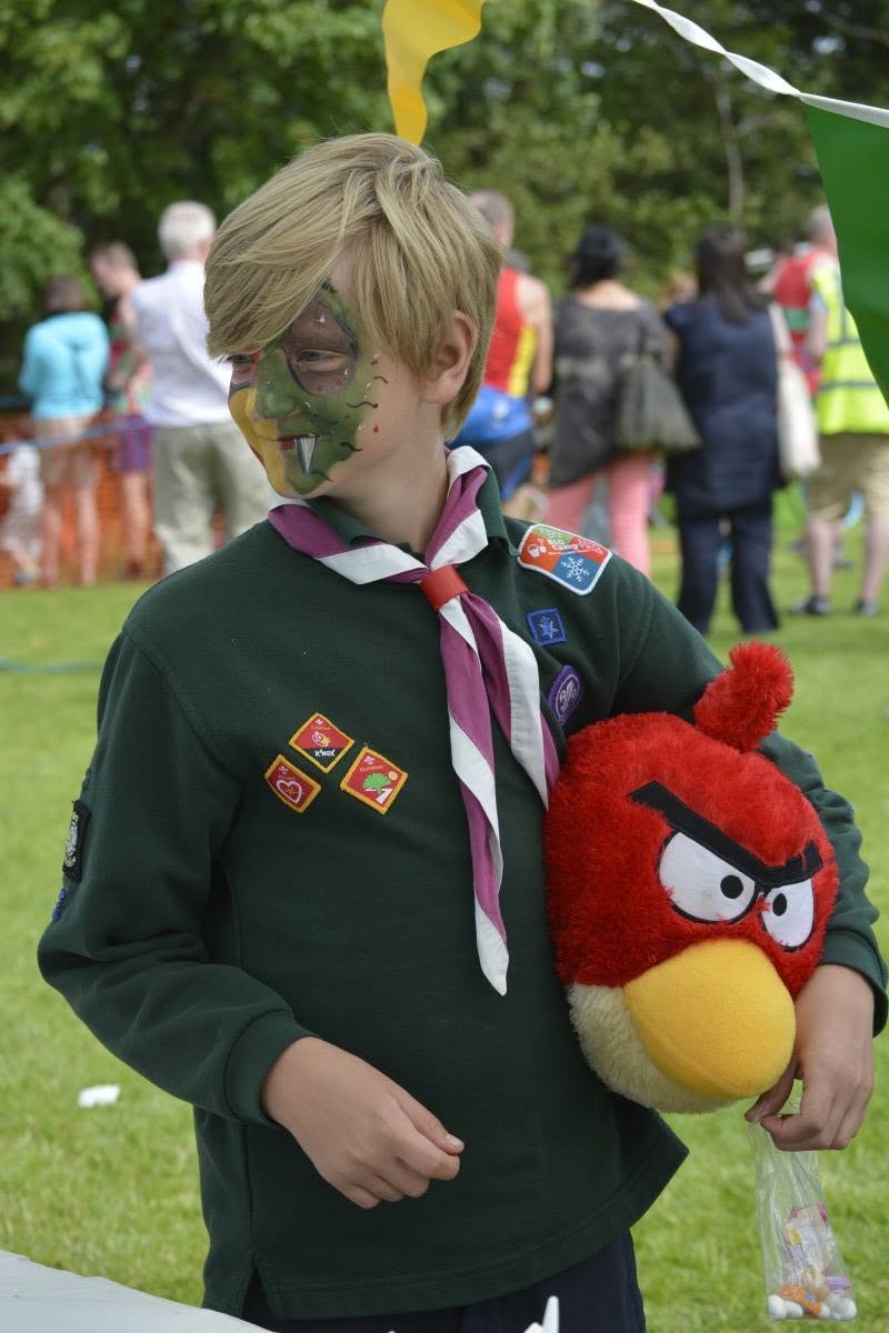 A child in Cubs uniform with face paint holding a soft-toy prize at the Addingham Gala
