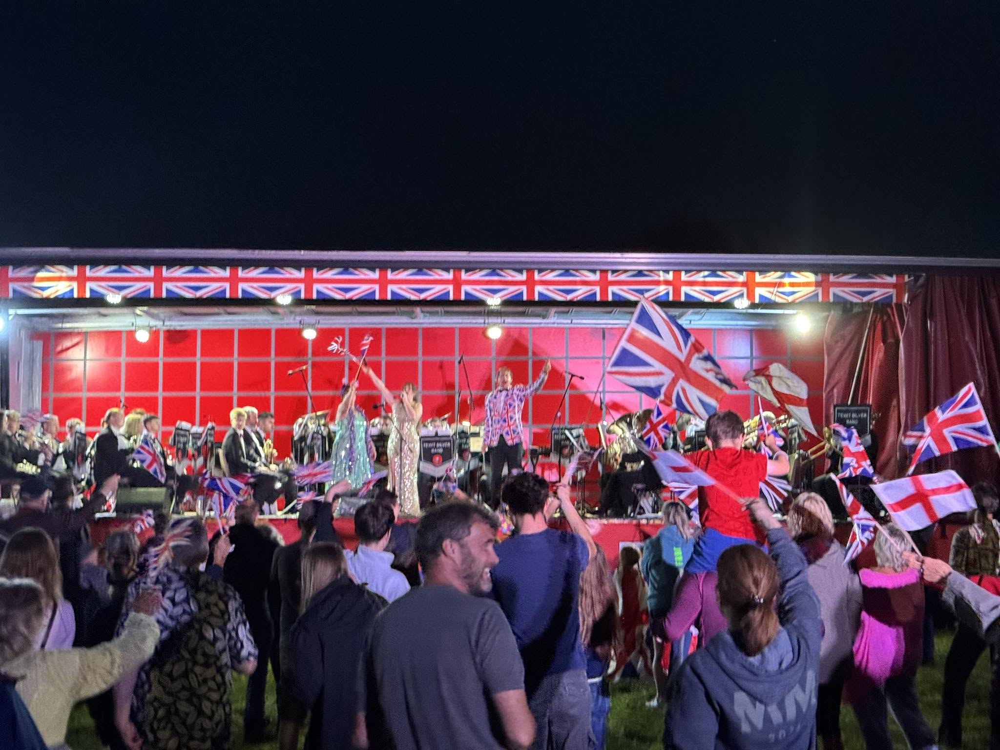 Flags waving in front of the band on stage at Silsden Proms on the Farm