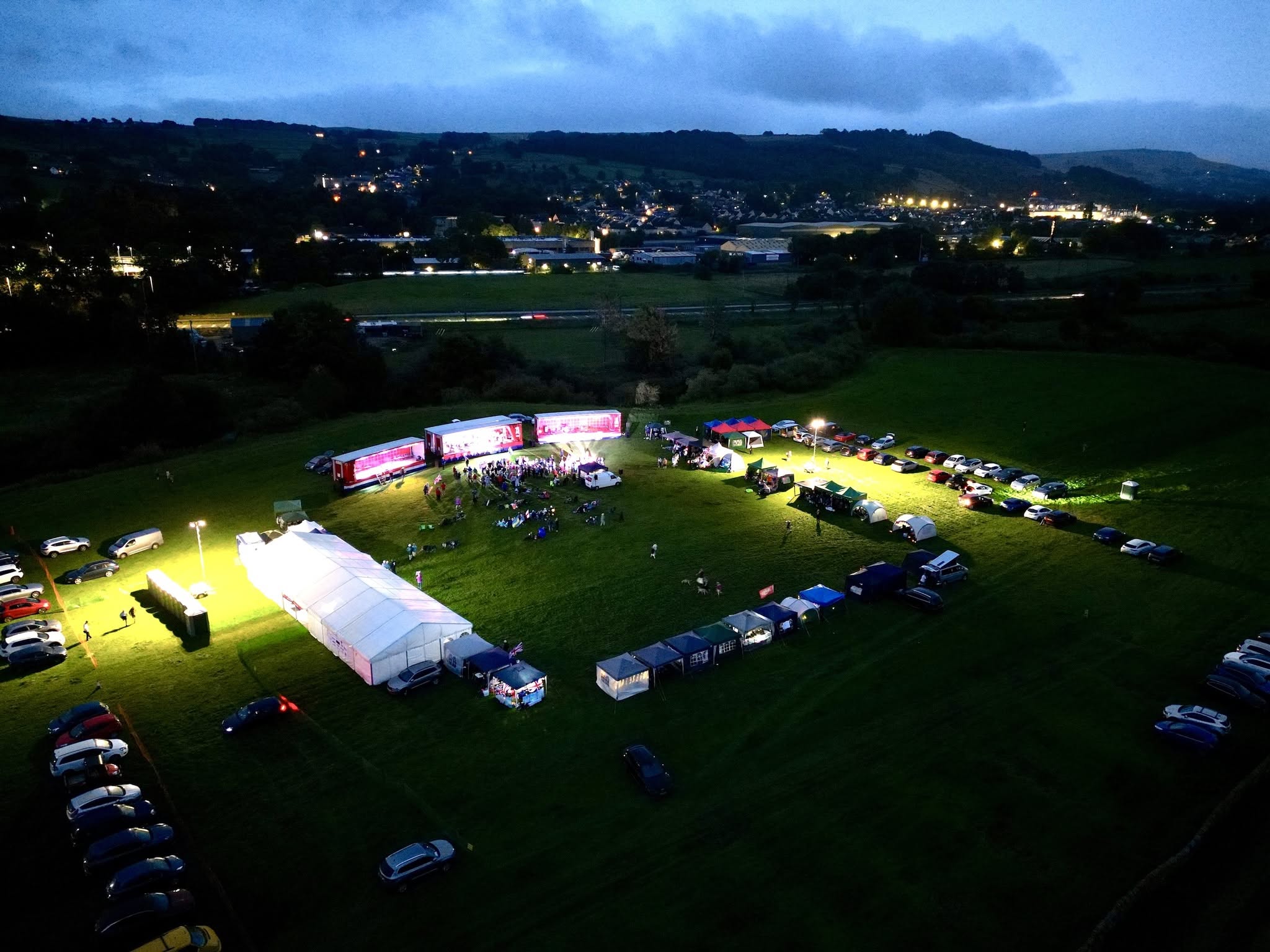 Evening view over the Proms on the Farm site at Jackson's Field, with the lights of Silsden beyond